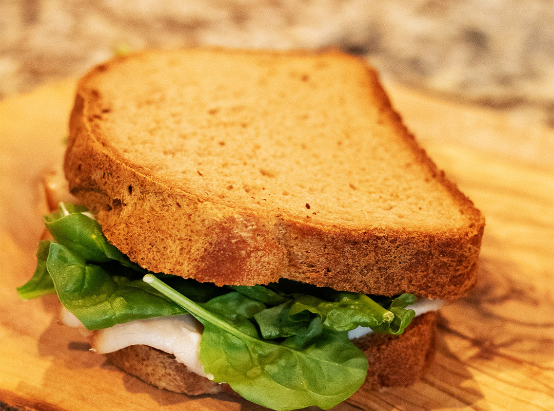 Sandwich with lettuce and tomato on Love That Bread gluten-free sandwich bread on a wooden board.