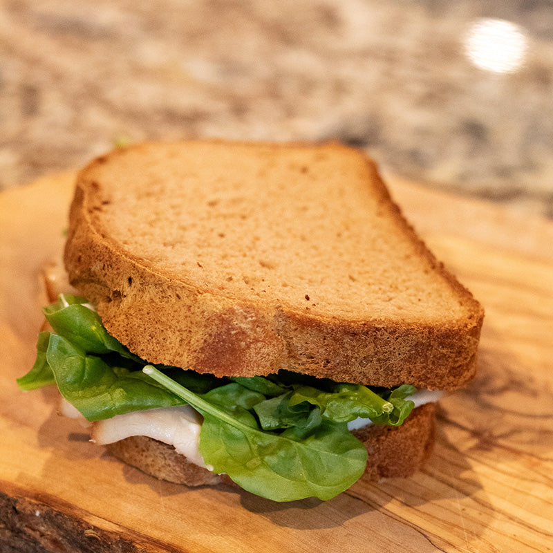 Love That Bread gluten-free bread mix sandwich with lettuce and tomato on whole grain bread on a wooden board.